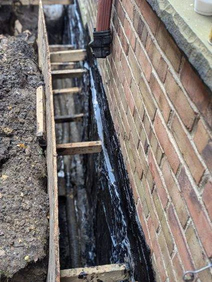 Exterior waterproofing membrane and drainage system installed along brick foundation