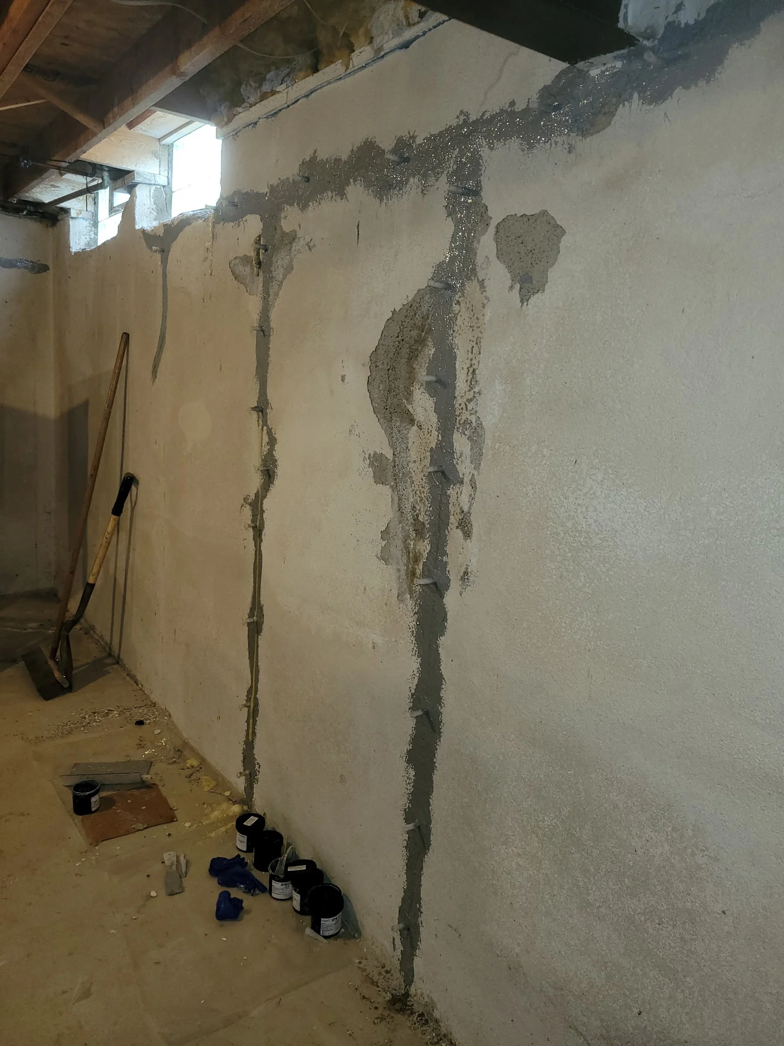 Interior basement wall with vertical crack being sealed using injection epoxy repair method