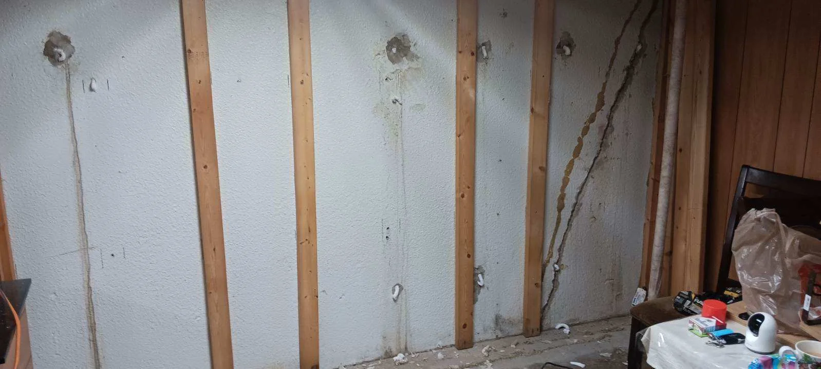 Basement wall with multiple injection ports installed in cracks between wooden studs